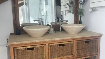 A wooden vanity with two large sinks, a mirror, and a ceiling light fixture.