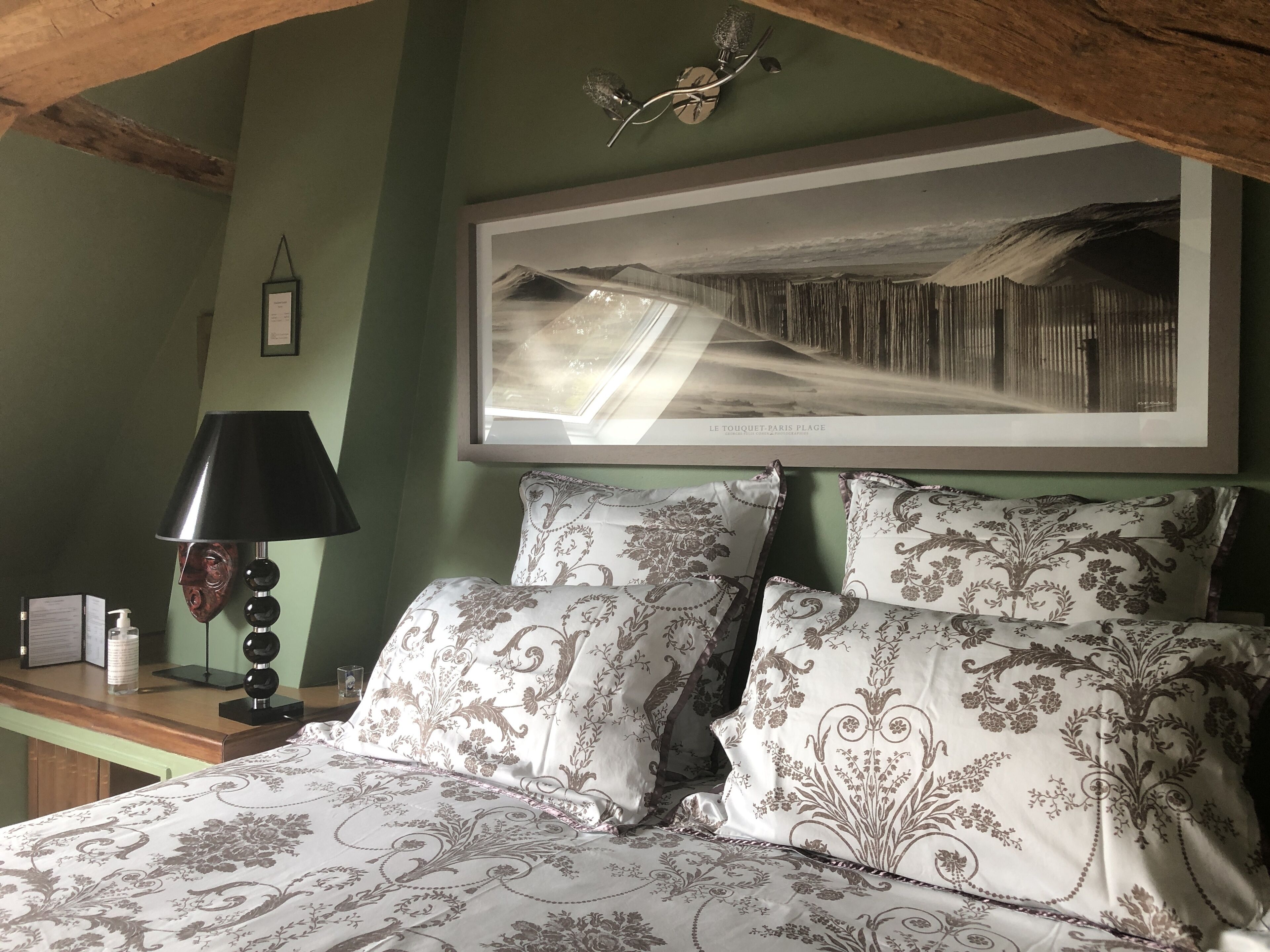 A bedroom with a bed, a nightstand, a lamp, and a framed picture on the wall.