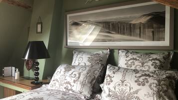 A bedroom with a bed, a nightstand, a lamp, and a framed picture on the wall.