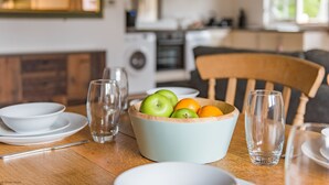 A dining table with a bowl of fruit, glasses, and plates. - Motor House Loft - beautiful loft conversion in lovely rural location by Bloom Stays (Sandhurst)