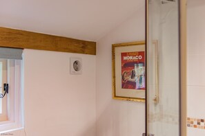 Un bagno con un poster incorniciato al muro, un portascopino e uno spazio doccia.