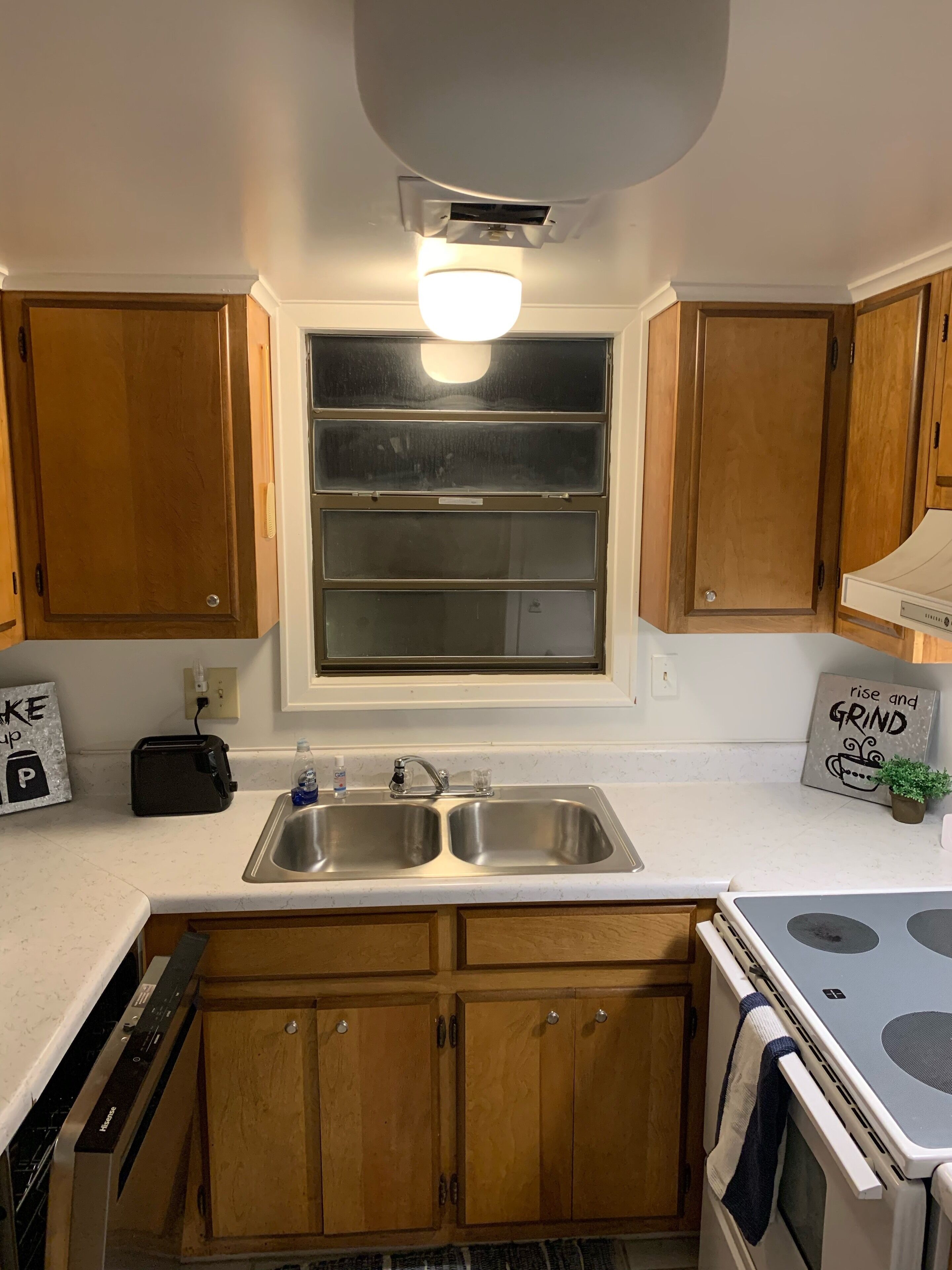 A kitchen with wooden cabinets, a double sink, a toaster, and a stove.