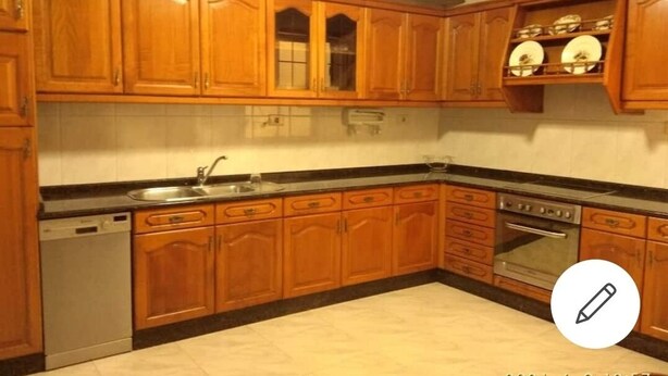 Uma cozinha com armários de madeira, lava-louças, forno e pia.