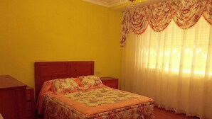 Quarto com cama, cabeceira de madeira, mesas de cabeceira e uma janela com cortinas.