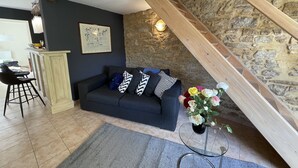 Ein gemütlicher Wohnbereich mit einem dunkelblauen Sofa, Holzboden und einer Steinwand.