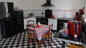 A kitchen with a checkered floor, a table with chairs, a refrigerator, a stove, a sink, and a kettle. - 3-bedroom vacation home. Le Faou Aulne Maritime Crozon  (LE FAOU)