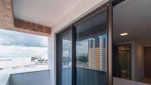 A balcony with a city view, a glass door leading to a bathroom, and a tiled floor. - GOLDFLAT Manaíra by Penareia.tur.br (João Pessoa)