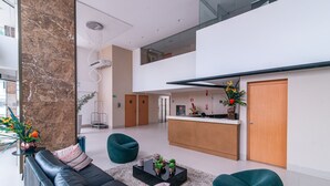 A modern living room with a black leather sofa, teal chairs, and a coffee table with decorative items. - GOLDFLAT Manaíra by Penareia.tur.br (João Pessoa)