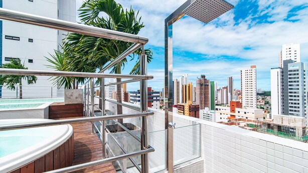 A rooftop pool area with a glass balustrade, a shower, and a view of the cityscape. - GOLDFLAT Manaíra by Penareia.tur.br (João Pessoa)