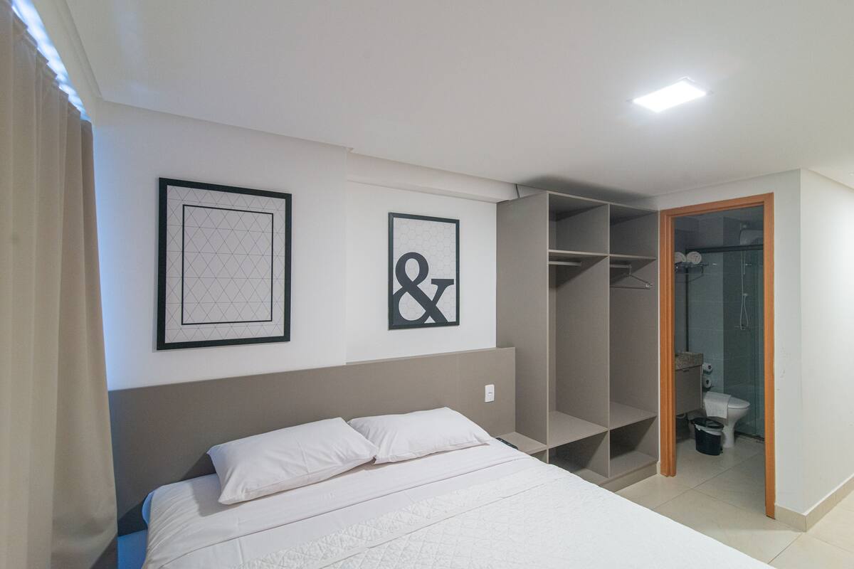 A bedroom with a bed, a wardrobe, and a bathroom visible through an open door.