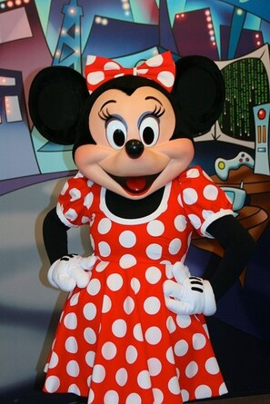 Un personaggio di Minnie Mouse con un abito rosso a pois e guanti bianchi.