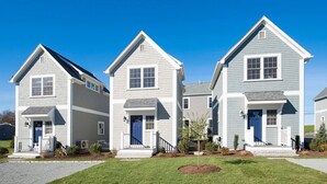 A row of three townhouses with a front porch, a small garden, and a clear blue sky. - Cottages with easy access to Newport, beaches, nature trails  and  vineyards (Middletown)