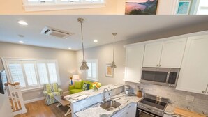 A modern kitchen with white cabinets, a built-in microwave, and a stainless steel range hood. - Cottages with easy access to Newport, beaches, nature trails  and  vineyards (Middletown)