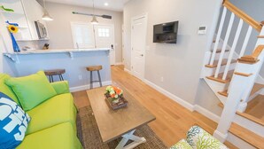 A modern living space with a kitchen, dining area, and a staircase. - Cottages with easy access to Newport, beaches, nature trails  and  vineyards (Middletown)