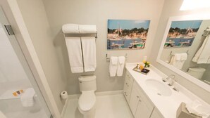 Un baño moderno con inodoro, lavamanos y un espejo grande.