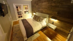 Une chambre à coucher avec un grand lit, une tête de lit en bois, une table de chevet et une étagère intégrée.
