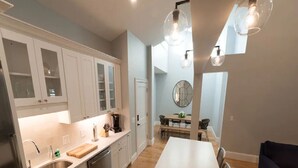 Une cuisine moderne avec des meubles blancs, un îlot central et des luminaires suspendus.