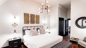 Ein modernes Schlafzimmer mit einem großen Bett, einem Nachttisch, einer Bank und Wanddekoration.
