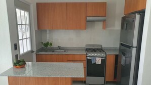 Eine moderne Küche mit Holzausstattung, einem Edelstahlkühlschrank, einem Gasherd und einer Spüle.