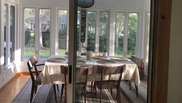 A dining area with a table set for four, large windows, and a view of the outdoors. - Fully Furnished Seneca Lake Lakefront Rental (Romulus)