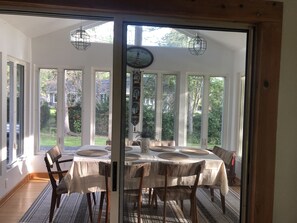 Un coin repas avec une table dressée pour quatre personnes, de grandes fenêtres et une vue sur l’extérieur.