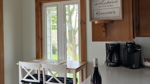 A kitchen with wooden cabinets, a coffee maker, a wine bottle, and a welcome sign. - Fully Furnished Seneca Lake Lakefront Rental (Romulus)