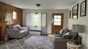 A living room with two sofas, a coffee table, a lamp, and a fireplace. - Fully Furnished Seneca Lake Lakefront Rental (Romulus)