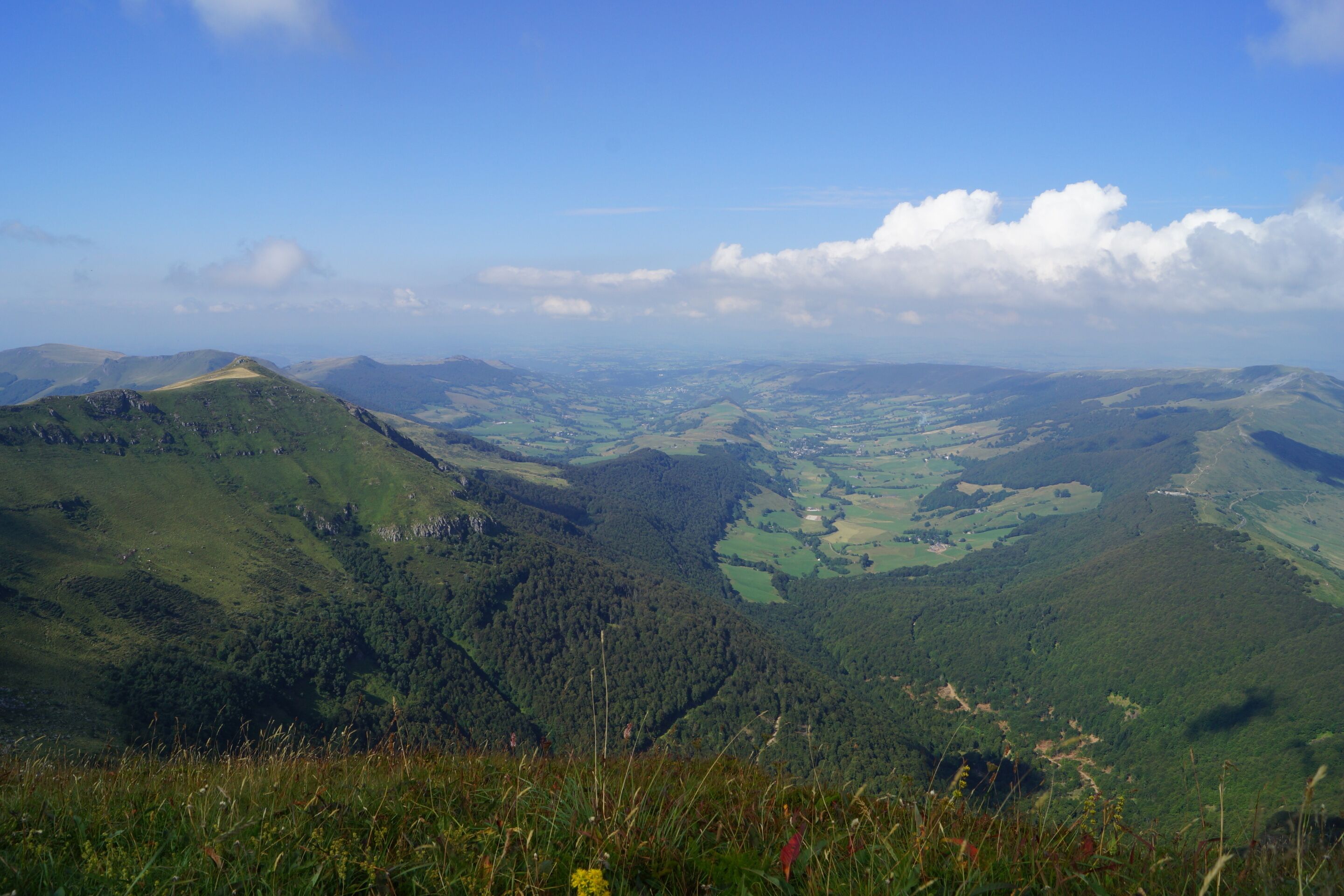 A panoramic view of a mountainous landscape with lush green valleys and distant hills.