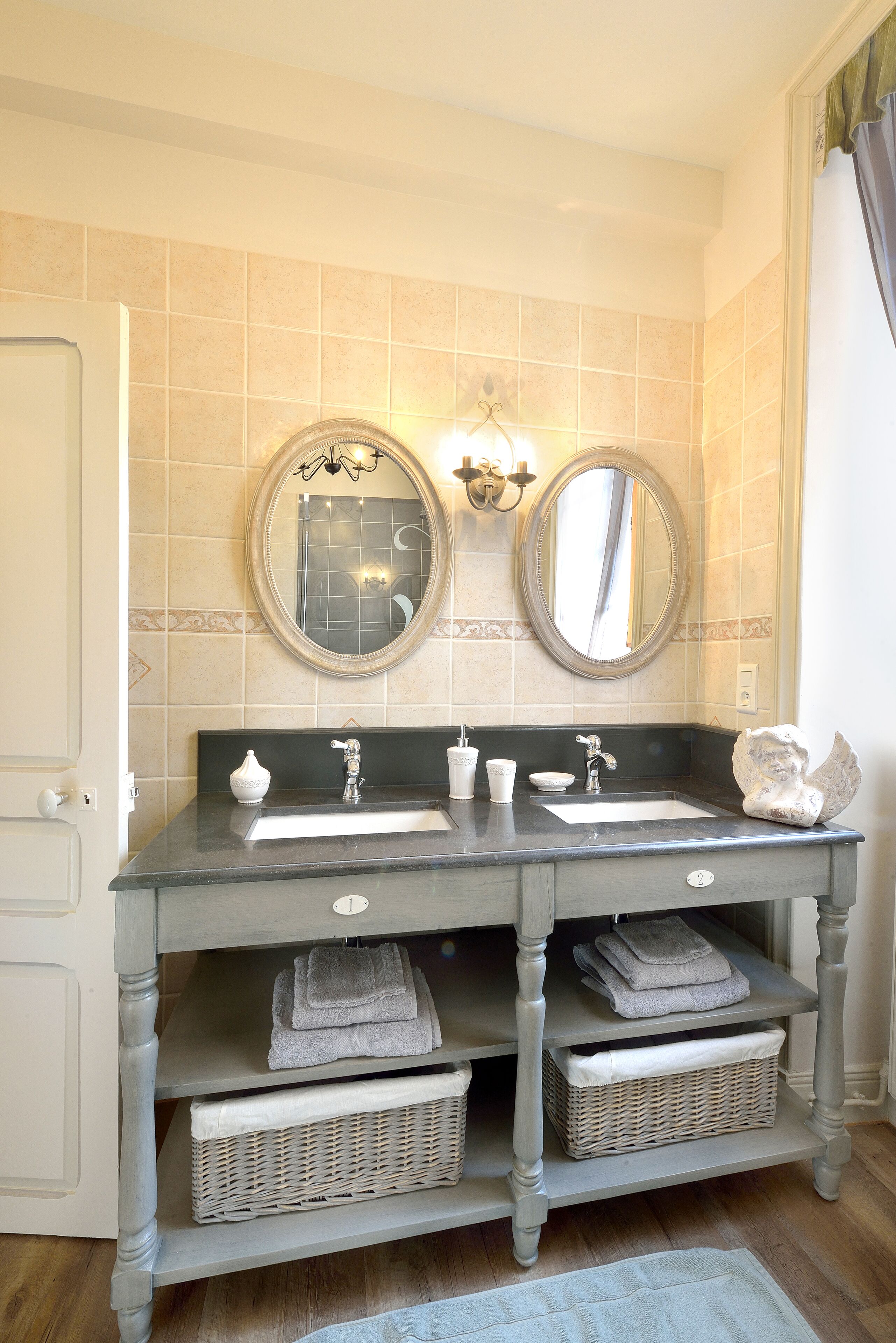 A bathroom with two sinks, a mirror, and a vanity with storage baskets.