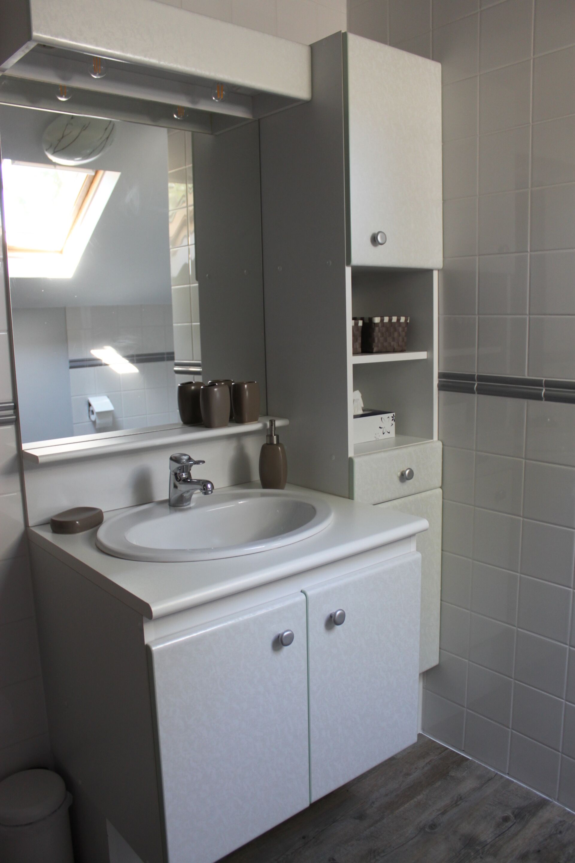 A bathroom with a white sink, mirror, and cabinets.
