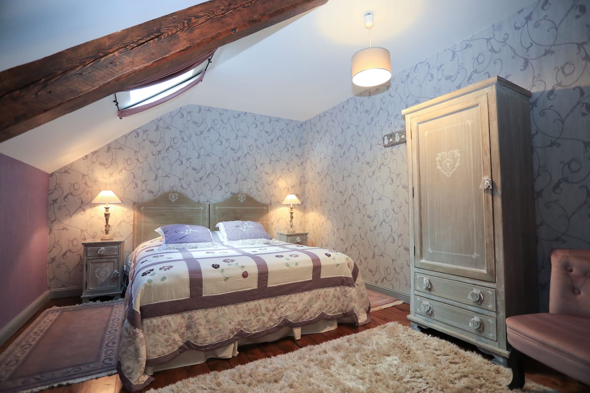 Ein Schlafzimmer mit Bett, Nachttischen, einem Kleiderschrank und einer Chandelüster.