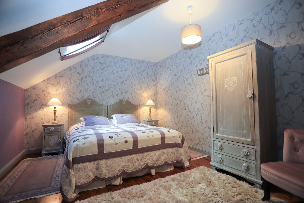 Ein Schlafzimmer mit einem Bett, zwei Nachttischen mit Lampen, einem Kleiderschrank und einem Sessel.