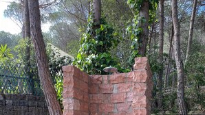 A brick structure with a small opening, surrounded by trees and a stone wall. - ♥️-lich Willkommen im la Dolce Vita -charming house with garden and terrace - (Narbolia, Loc. Is Arenas)