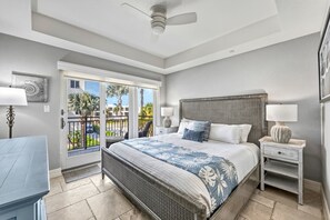 A bedroom with a bed, nightstands, a ceiling fan, a balcony with a view, and a door. - At Sun Sea Terrace | Luxury Siesta Key Condo w/ Heated Pool, Short Walk to Beach and Village (Siesta Key)