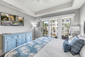 Un dormitorio con cama, cómoda y vistas a una piscina y edificios.