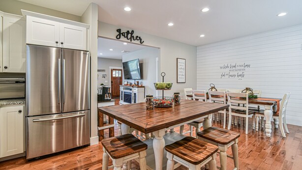 Una cocina moderna con refrigerador de acero inoxidable, mesa de comedor de madera y armarios blancos.
