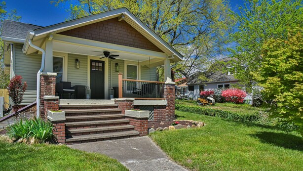 A two-story house with a front porch, brick steps, and a small garden.