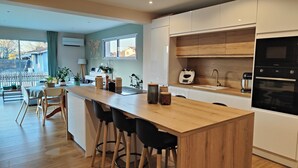 A modern kitchen with a wooden island, white cabinets, and a built-in oven. - Detached house with swimming pool between Arcachon and Bordeaux (Cestas) (Cestas)