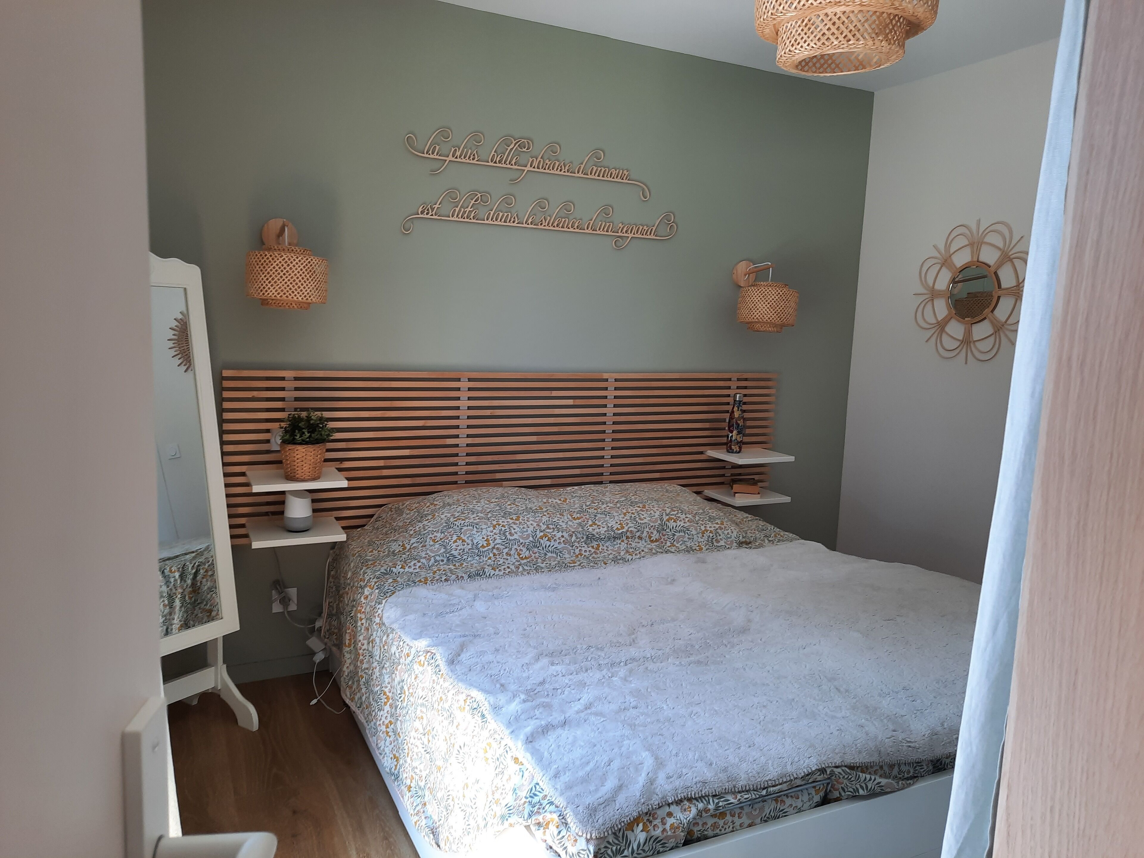 A bedroom with a bed, bedside tables, a mirror, and wall decor.