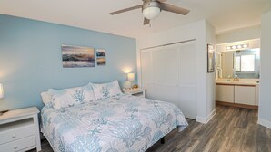 Une chambre à coucher avec un lit, une table de chevet et un ventilateur de plafond.