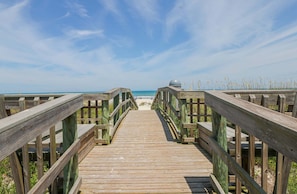 A wooden boardwalk leading to a beach with a clear sky.