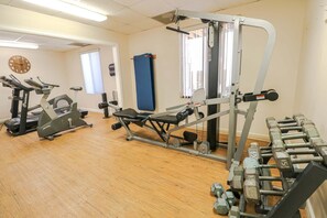 A gym with cardio machines, weightlifting equipment, and a blue mat.