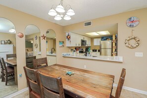 Un comedor con una mesa y sillas de madera, una cocina al fondo y elementos decorativos en la pared.