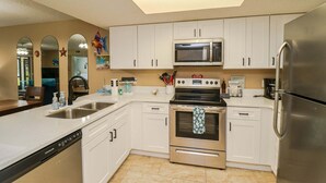 A kitchen with white cabinets, stainless steel appliances, a dishwasher, and a microwave. - Ocean Villlage Club Condo G16 (St. Augustine)