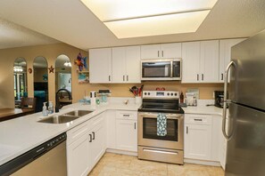 A kitchen with white cabinets, stainless steel appliances, a dishwasher, and a microwave.
