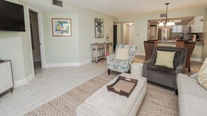 A living room with a sofa, armchairs, a coffee table, and a TV.