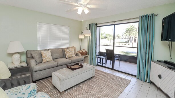 A living room with a sofa, ottoman, lamp, and TV.
