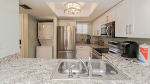 A modern kitchen with stainless steel appliances, granite countertops, and white cabinetry.