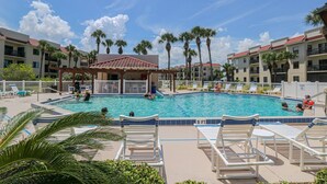 A pool area with lounge chairs, palm trees, and a covered pavilion. - Ocean Village Club Condo R28 (St. Augustine)