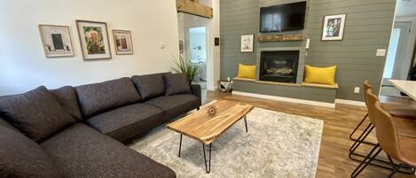 A modern living room with a sectional sofa, a wooden coffee table, and a fireplace.